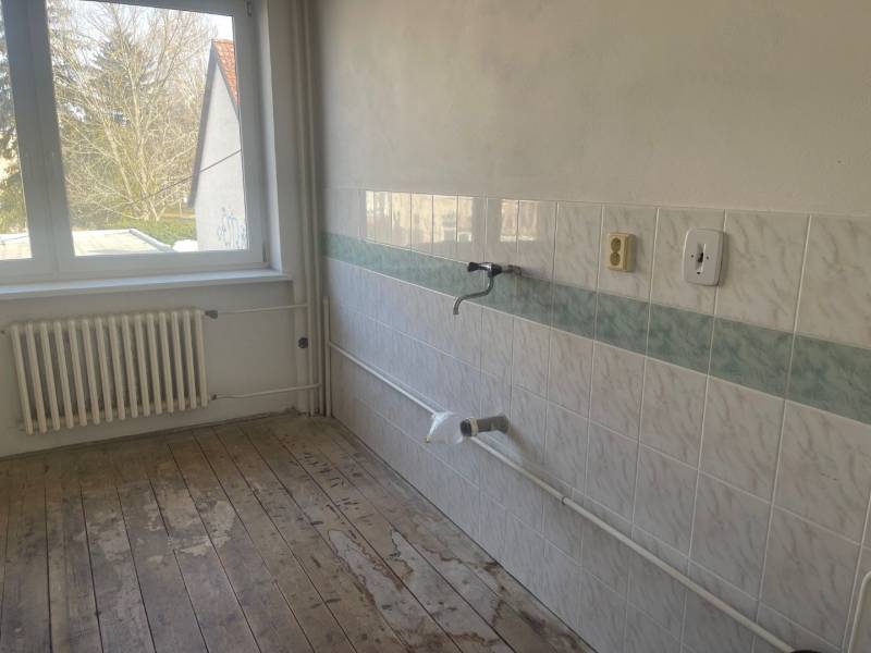 Üres konyha egy családi házban csempével és fa padlóval.