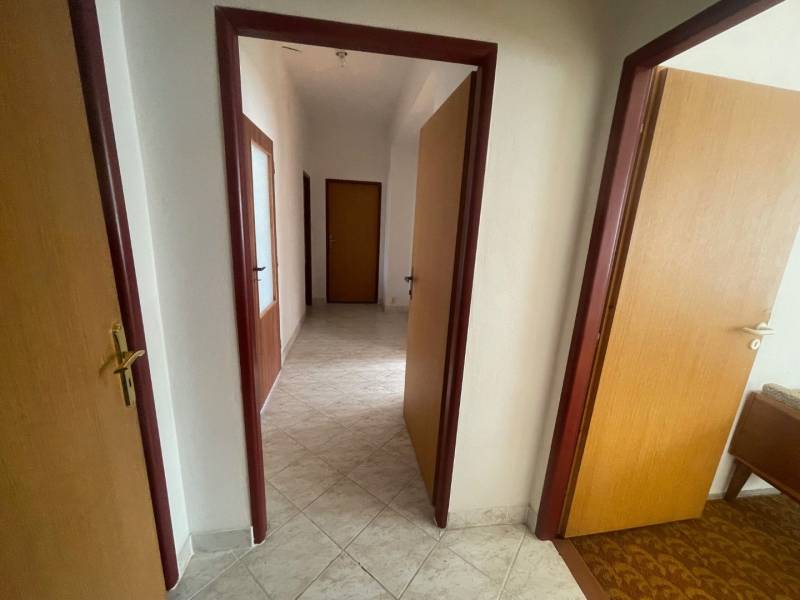 Családi ház belső tere folyosóval, ajtókkal és világos csempékkel.
