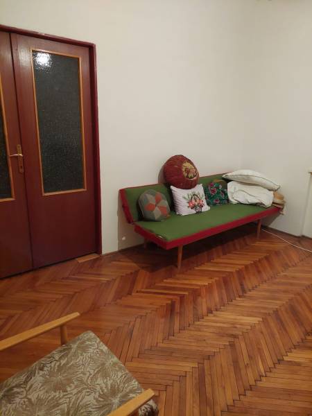 Családi ház belső tere fa padlóval, kanapéval és párnákkal a szoba sarkában.