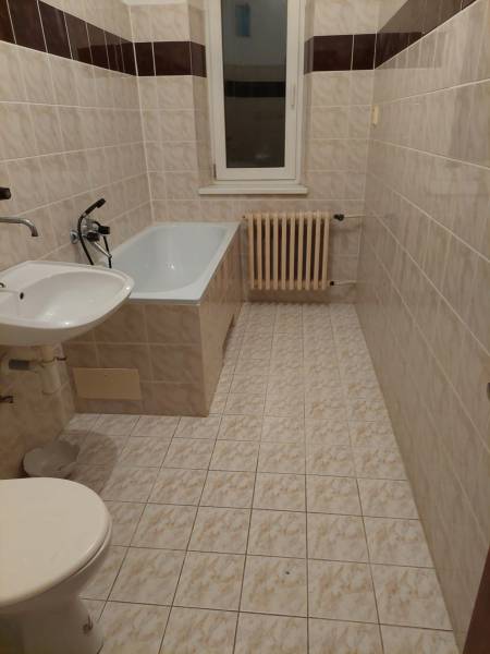 Fürdőszoba egy családi házban káddal, mosdóval, WC-vel és fali radiátorral.