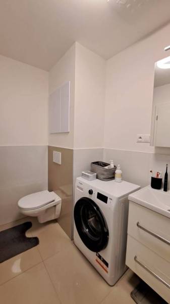 Fürdőszoba egy kétszobás lakásban mosógéppel, mosdóval és WC-vel.