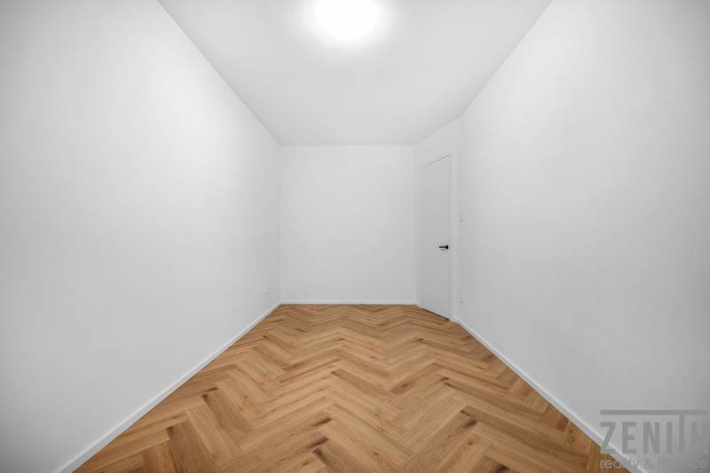 Egy üres szoba fehér falakkal és fa padlóval egy háromszobás lakásban.