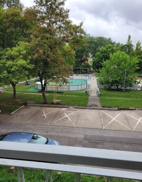 Kilátás egy háromszobás lakásból Pozsonyban - Ružinovban, a Mesačná utcában, parkoló, fák és játszótér.
