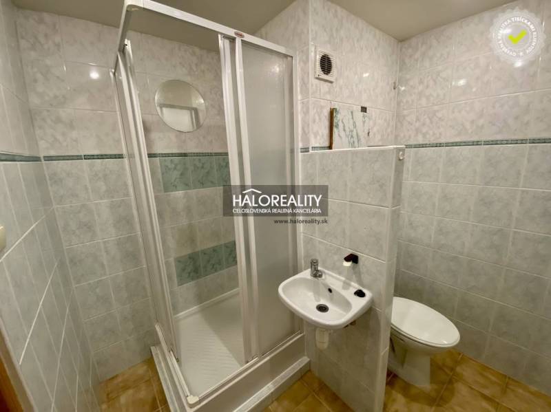 Fürdőszoba egyszerű zuhanyzóval, mosdóval és WC-vel egy egyszobás lakásban.