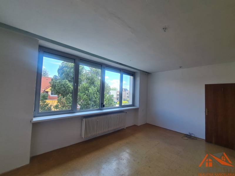 Üres szoba nagy ablakkal, faajtóval és radiátorral egy családi házban.