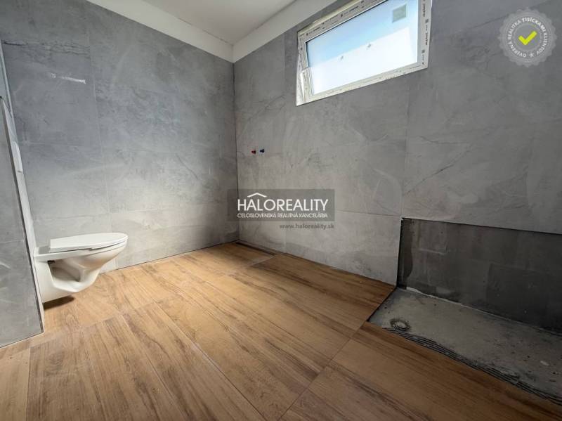 Fürdőszoba egy családi házban csempével és szabadon álló WC-vel, befejezésre vár.