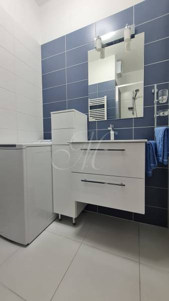 Fürdőszoba egy kétszobás lakásban, szekrénnyel, mosdóval és tükörrel a falon.