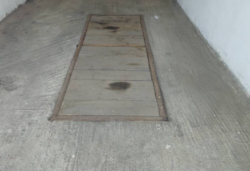 Betonpadló a garázsokban középen egy aknafedéllel.