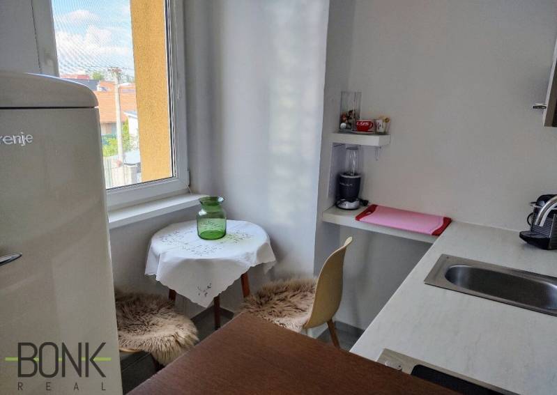 Konyha egy kétszobás lakásban ablakkal, bárpulttal és étkező sarokkal.