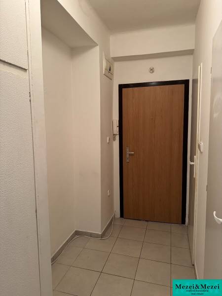 Folyosó világos csempével és faajtókkal egy kétszobás lakásban.