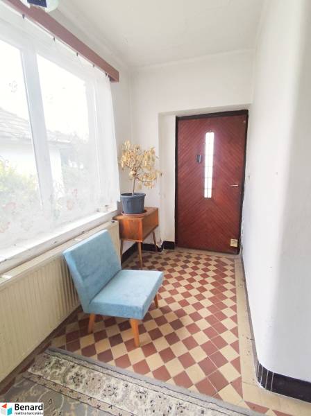 Családi ház előszobája virágcseréppel, kék székkel és sakktáblás padlóval.