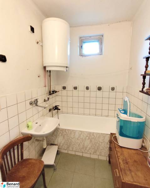 Családi ház fürdőszobája káddal, mosdóval, mosógéppel és vízmelegítővel.