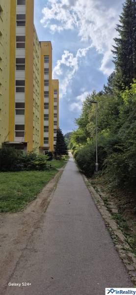 Sárga lakóház a Moszkva utcában Besztercebányán, a járda és a zöldterület mellett.