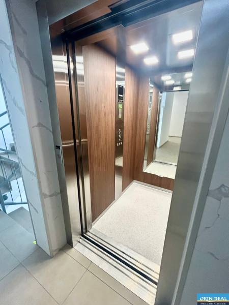 Nyitott lift egy 3 szobás lakásban fa burkolattal és világítással.