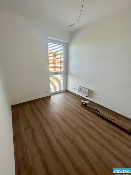 Üres szoba laminált padlóval és nagy ablakkal egy háromszobás lakásban.