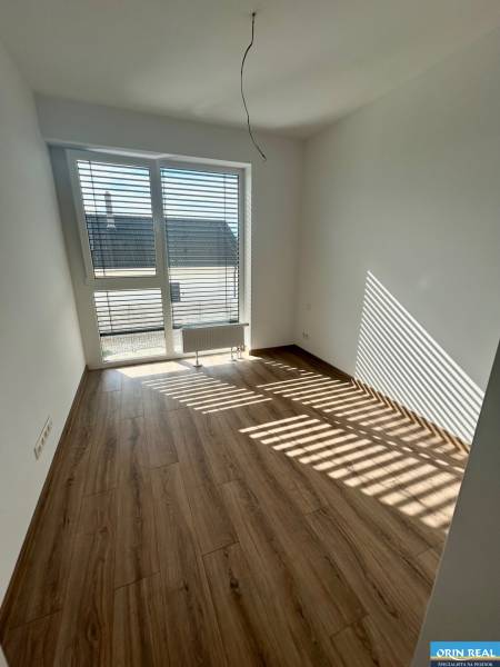 Szoba egy háromszobás lakásban laminált padlóval és nagy ablakkal.
