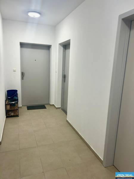 Folyosó egy 3 szobás lakásban ajtókkal és világítással, járólap a padlón.