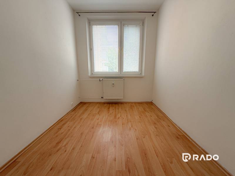 Üres szoba ablakkal és radiátorral, fa padló, 3 szobás lakás.