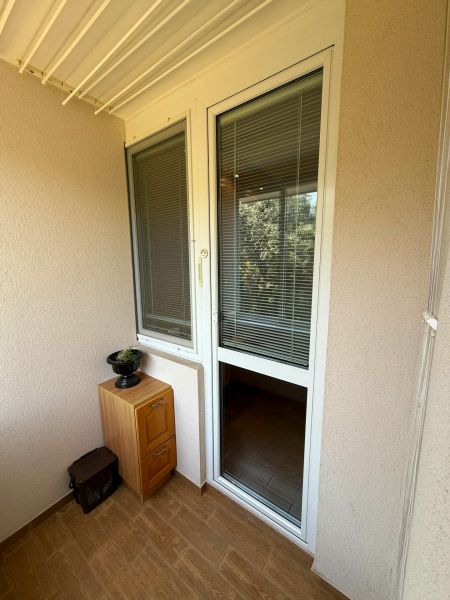 Erkély egy 3 szobás lakásban, fa mintázatú padlóval és szekrénnyel.