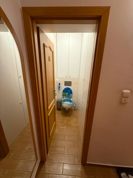 WC csempével és dekoratív ülőkével egy háromszobás lakásban.