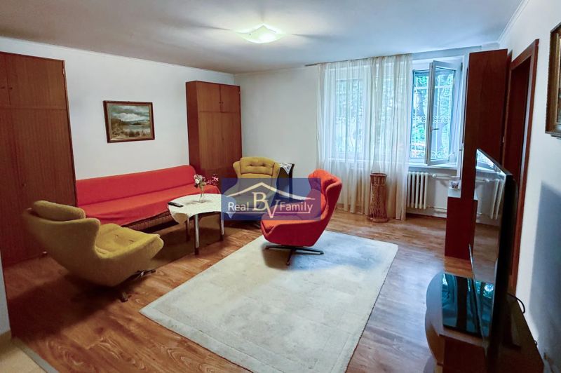 Nappali egy kétszobás lakásban retro bútorokkal és fa dekorációjú padlóval.