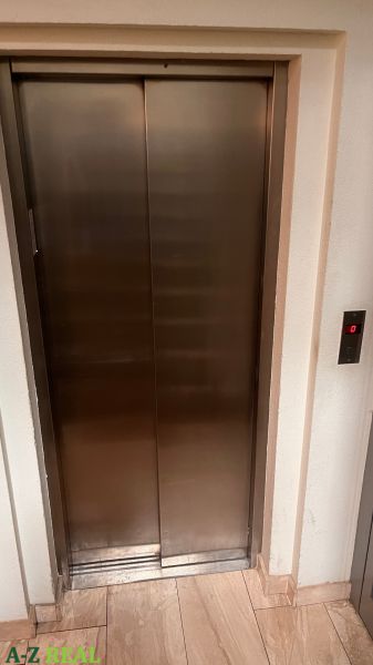 Rozsdamentes acél lift az irodában, fa mintázatú padlóval.