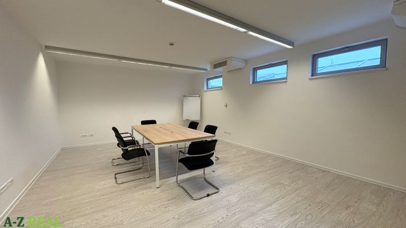 Irodák fa dekorációjú padlóval, konferenciaasztallal és székekkel.
