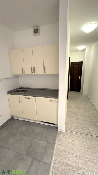 Irodák fehér konyhapulttal és szürke csempékkel, fa dekorral ellátott padló.