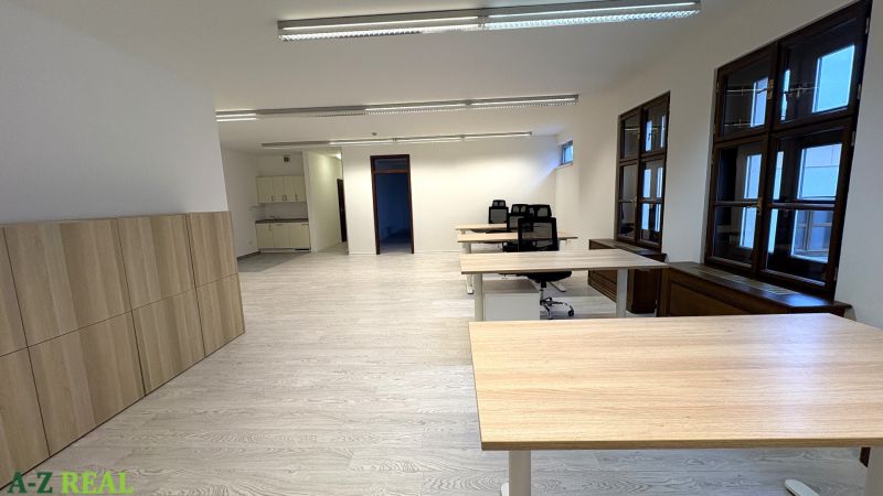 Irodák fa dekor padlóval, íróasztalokkal és modern világítással.