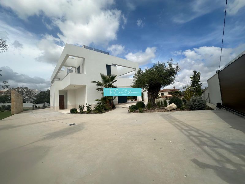 Villa Benissében minimalista építészet és gondozott kert a kék ég alatt.