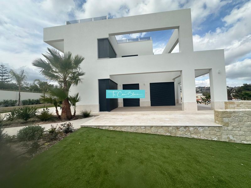 Fehér homlokzatú villa Benissában, pálmafákkal és füves területtel a kertben.