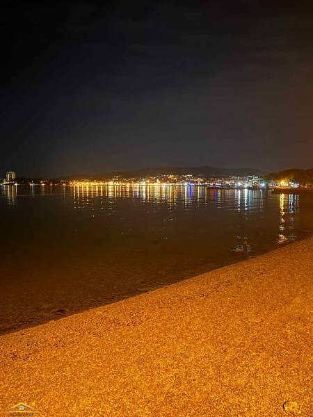 Éjszakai strand Vodice városában, Horvátország, a városi fények tükröződésével a vízen.
