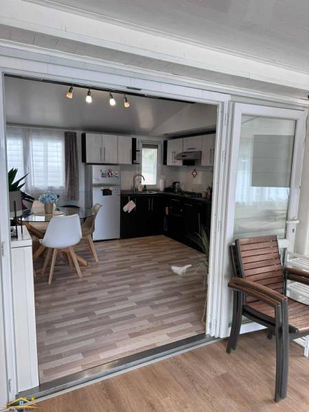 Belső tér világos asztallal, székekkel, konyhapulttal és fa dekorációjú padlóval.