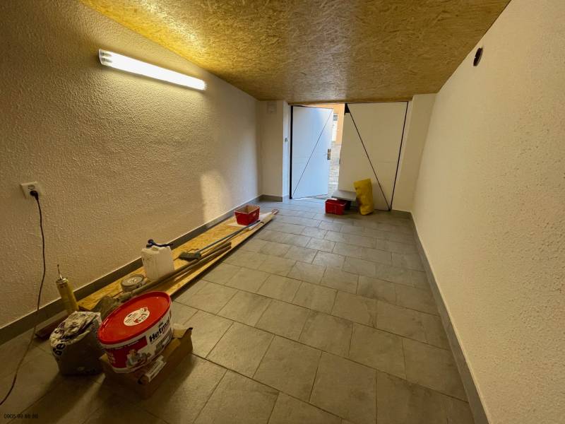 Szerszámokkal és világítással ellátott garázsok, fa dekorú padló, nyitott ajtó a nappali fényhez.