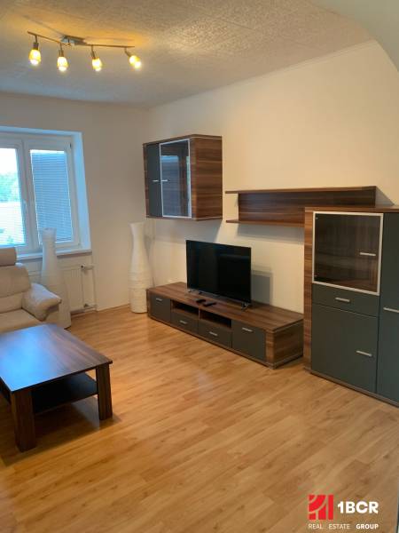 Nappali egy kétszobás lakásban fa dekor padlóval és televízióval.