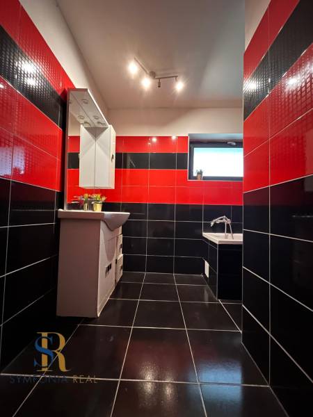 Fekete-piros fürdőszoba családi házban tükörrel és káddal, feltűnő csempekombináció.