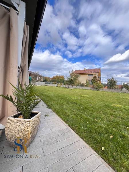 A Lipová utcai családi ház kertje Dubovában, gyepes területtel és kövezett járdával.