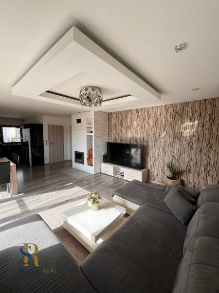 Nappali a családi házban kanapéval, TV-vel és kandallóval, fa dekorációjú padlóval.