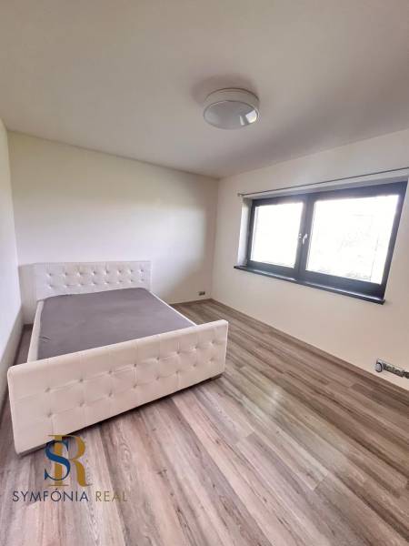 Hálószoba családi házban, ággyal és fa dekorációjú padlóval.