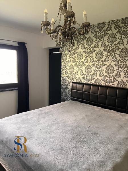 Hálószoba családi házban dekoratív tapétával és csillárral. Az enteriőr dizájn szimfóniája.