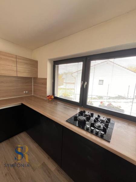 Konyha fa dekorációval és pulttal egy családi házban, ablakkal és gázfőzővel.