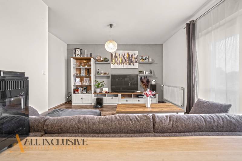 Nappali egy kétszobás lakásban fa hatású padlóval és nagy kanapéval.