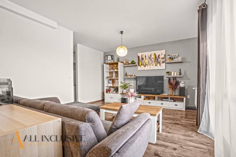 Nappali egy kétszobás lakásban, fa dekoros padlóval, kényelmes ülőgarnitúrával és dekorációkkal.