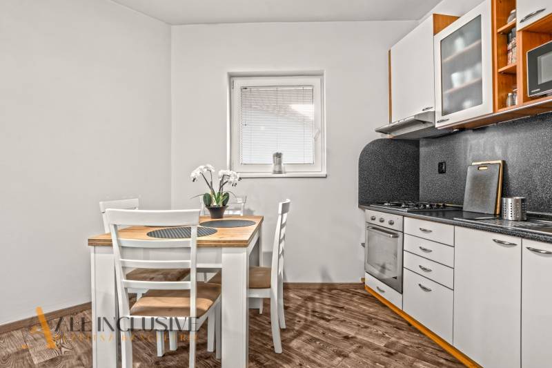 Konyha egy kétszobás lakásban étkezőasztallal és fa dekorációjú padlóval.