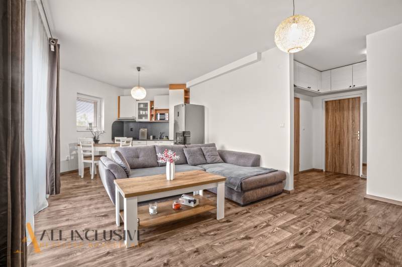 Nappali egy kétszobás lakásban kanapéval és fa dekorációjú padlóval.