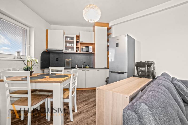 Konyha egy kétszobás lakásban fa dekor padlóval és étkezőasztallal.