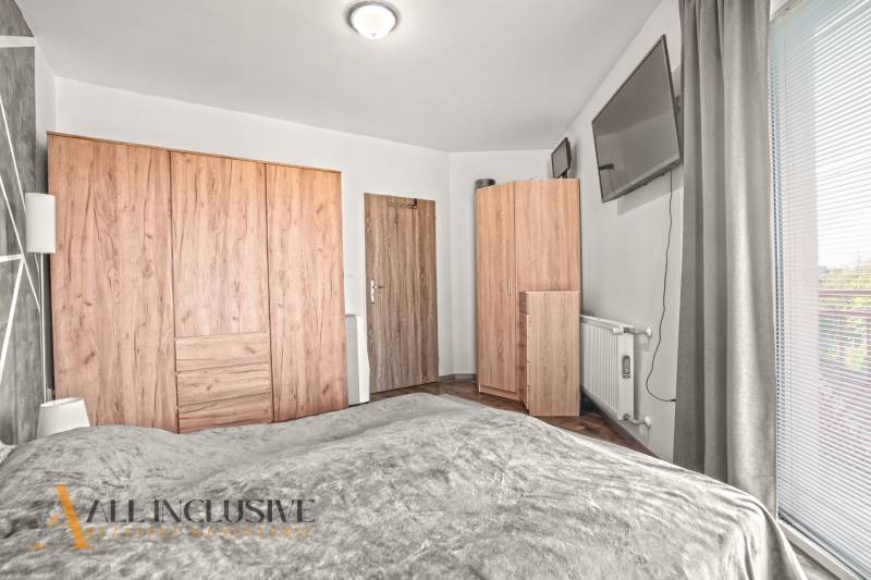 Hálószoba egy kétszobás lakásban fa dekor padlóval és ruhásszekrényekkel.