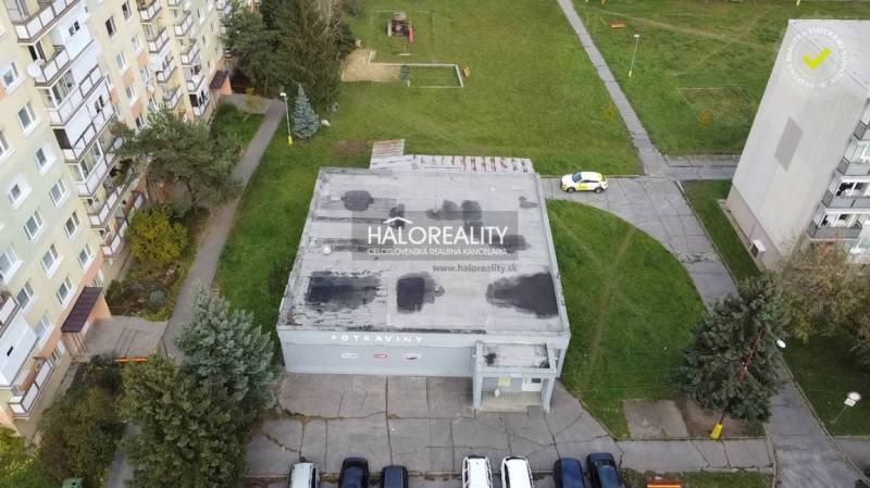 Kereskedelmi helyiségek Rimaszombatban lapos tetővel, zöldövezettel és lakóházakkal körülvéve.