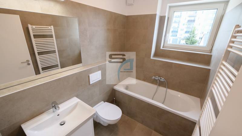 Fürdőszoba egy kétszobás lakásban káddal, mosdóval, tükörrel és ablakkal.