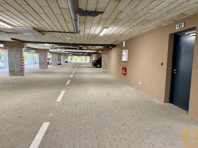 Parkolóhelyekkel és jelzésekkel ellátott parkoló, burkolata térkő, a garázsokban.